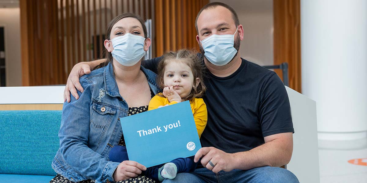 A family holds a sign that reads "Thank You"