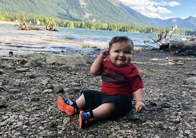 A boy sitting on the bank of a river