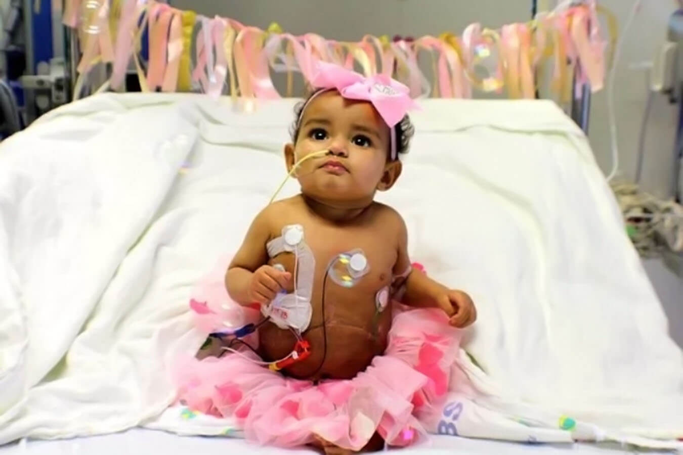 A girl wears a pink tutu in her hospital bed