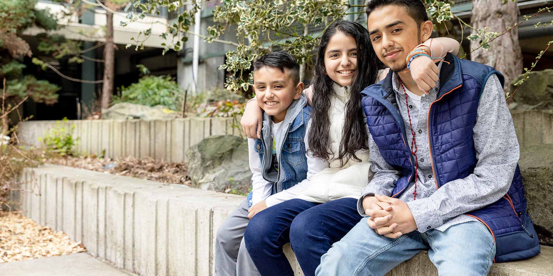 Three children sit under a tree