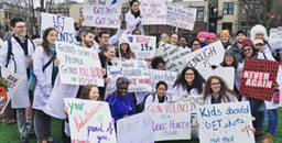 Residents participating in a rally hold up signs