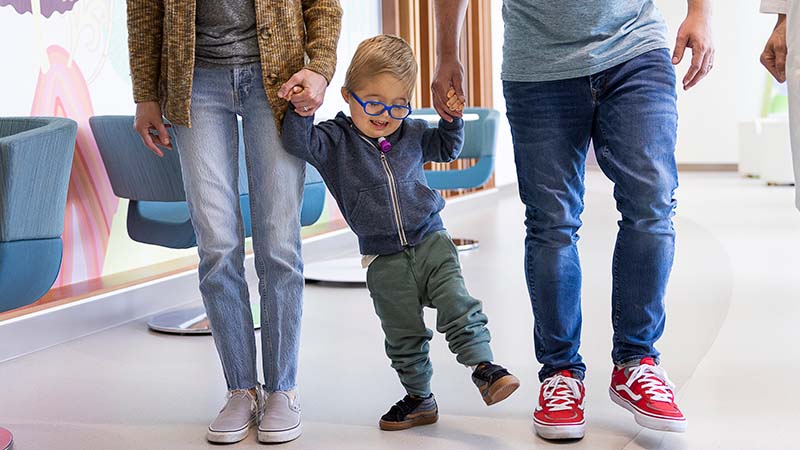 A boy holds hands with his parents.